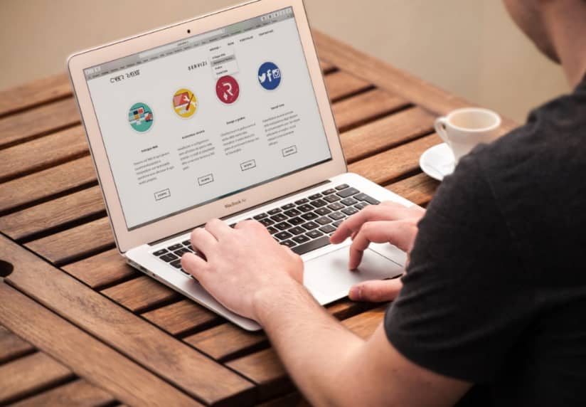 man using macbook with coffee